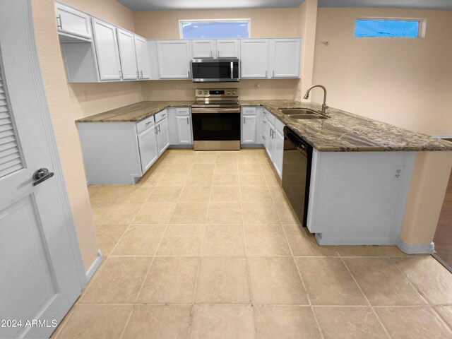 kitchen featuring sink, light tile patterned floors, stainless steel appliances, kitchen peninsula, and white cabinets