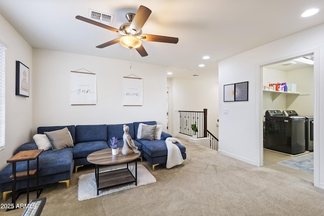 living room with ceiling fan, light colored carpet, and independent washer and dryer