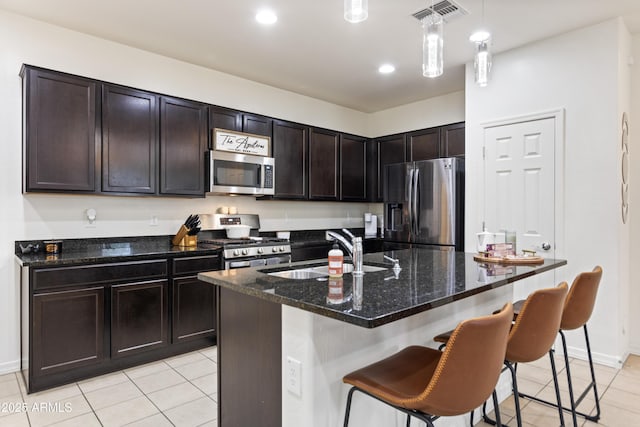 kitchen with pendant lighting, appliances with stainless steel finishes, sink, a kitchen island with sink, and light tile patterned floors