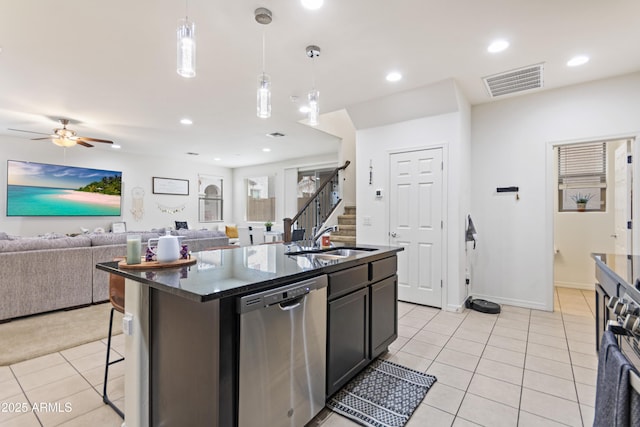 kitchen featuring an island with sink, light tile patterned flooring, pendant lighting, stainless steel dishwasher, and sink