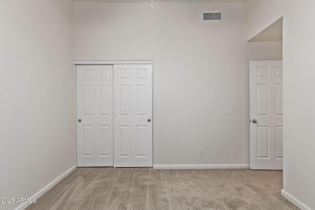 unfurnished bedroom with light carpet and a closet