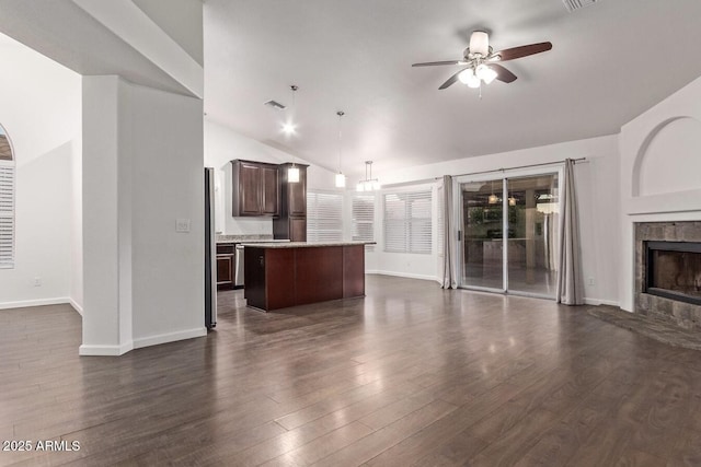 unfurnished living room with dark wood-type flooring, ceiling fan, lofted ceiling, and a tile fireplace