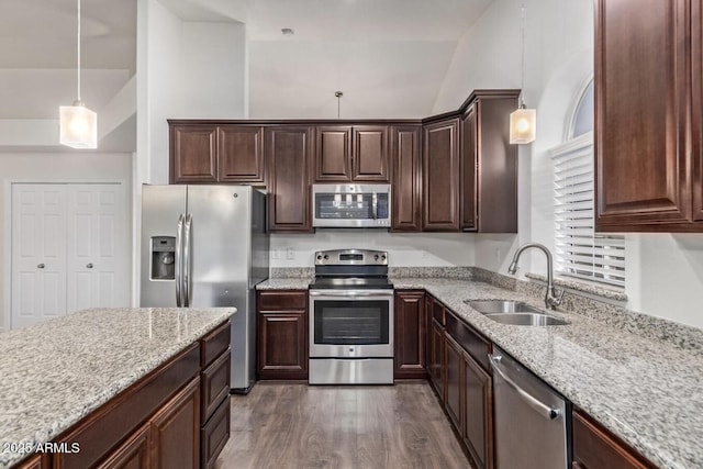 kitchen with sink, dark wood-type flooring, appliances with stainless steel finishes, hanging light fixtures, and light stone counters