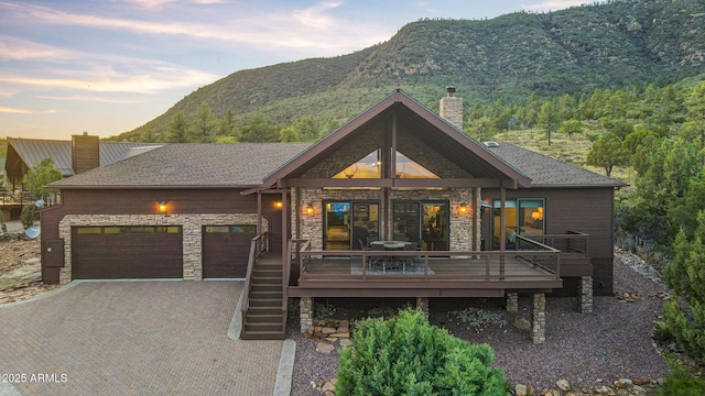 4562 N Dream Catcher Way, Pine, AZ 85544 - view of front of property with a chimney, decorative driveway, stone siding, an attached garage, and a deck with mountain view
