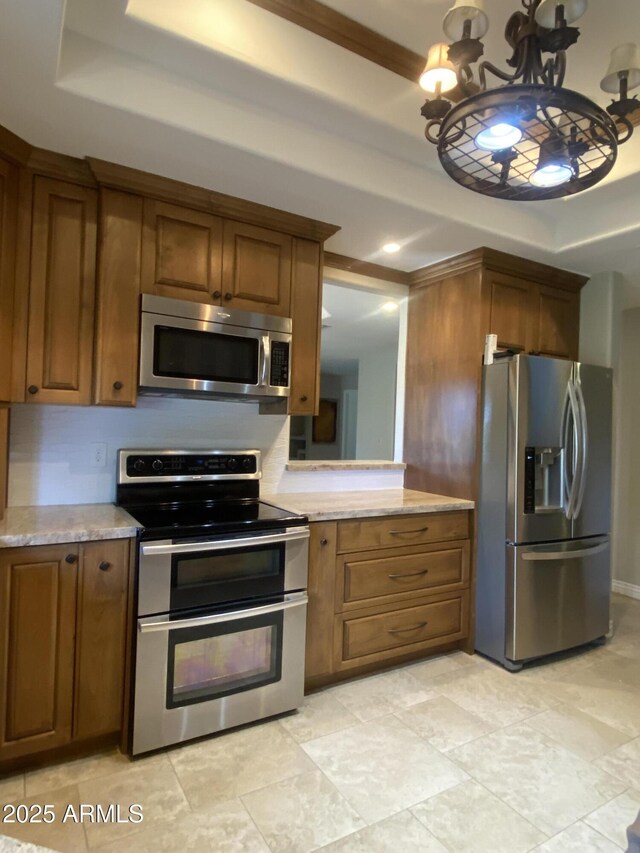 19322 E Calle De Flores, Queen Creek, AZ 85142 - kitchen with a tray ceiling, stainless steel appliances, brown cabinetry, and a notable chandelier