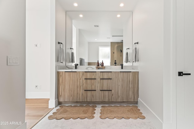 full bath with a sink, double vanity, baseboards, recessed lighting, and wood finished floors