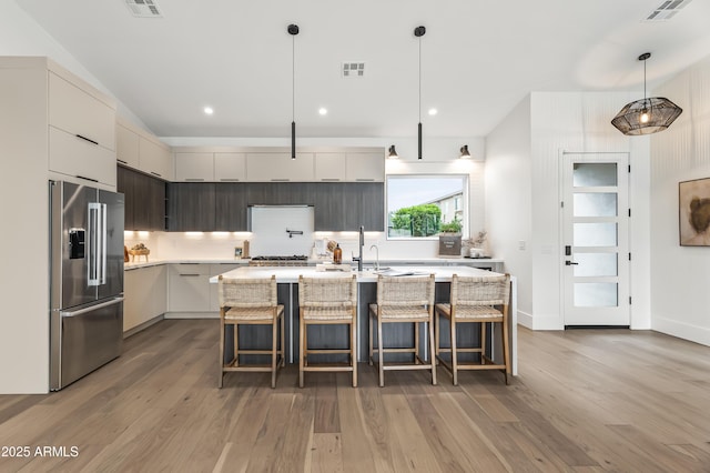 kitchen with modern cabinets, high end fridge, light wood-style floors, and visible vents