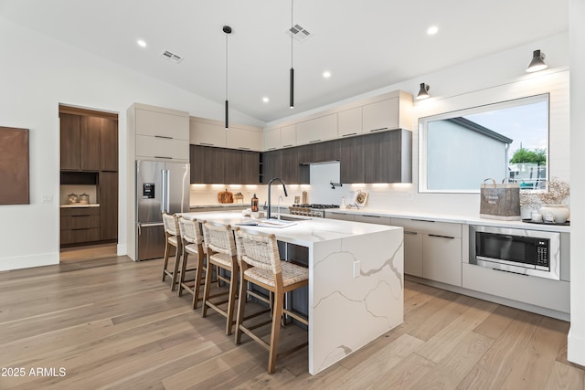 kitchen with modern cabinets, visible vents, built in microwave, and high end fridge