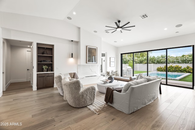 living room with lofted ceiling, visible vents, and light wood-style flooring