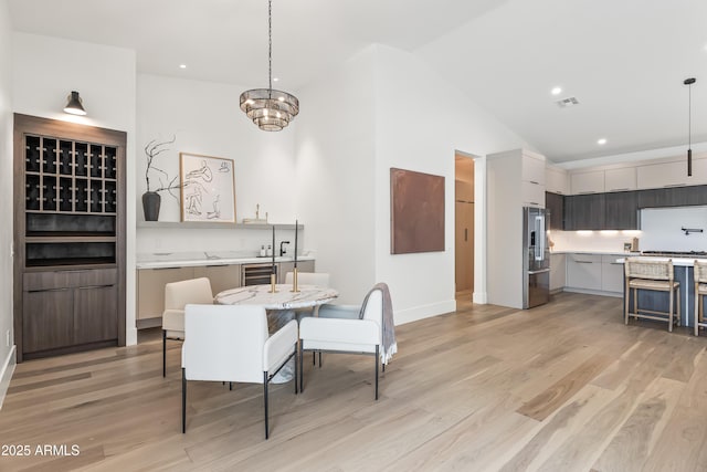 dining space with baseboards, beverage cooler, light wood finished floors, and visible vents