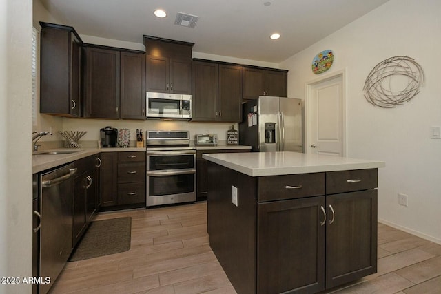 kitchen with a kitchen island, appliances with stainless steel finishes, sink, and dark brown cabinetry