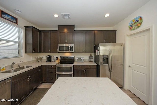 kitchen with hardwood / wood-style floors, stainless steel appliances, sink, and dark brown cabinets