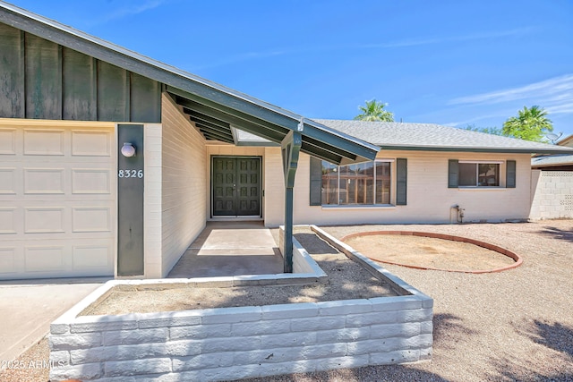 8326 E Valley View Rd, Scottsdale, AZ 85250 - property entrance featuring an attached garage, a shingled roof, and board and batten siding