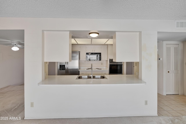 8326 E Valley View Rd, Scottsdale, AZ 85250 - kitchen with black appliances, a sink, a peninsula, light countertops, and a textured ceiling