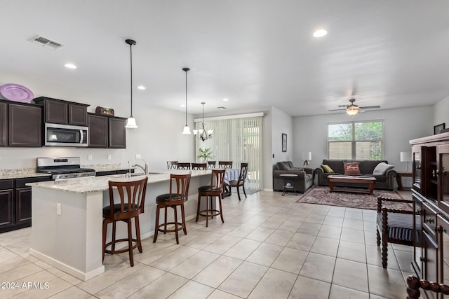 kitchen with light tile patterned floors, dark brown cabinetry, a breakfast bar, visible vents, and appliances with stainless steel finishes