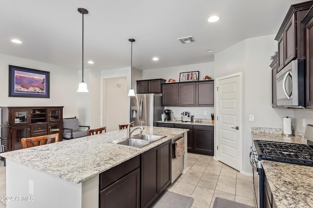 kitchen with a kitchen island with sink, dark brown cabinetry, stainless steel appliances, a sink, and visible vents