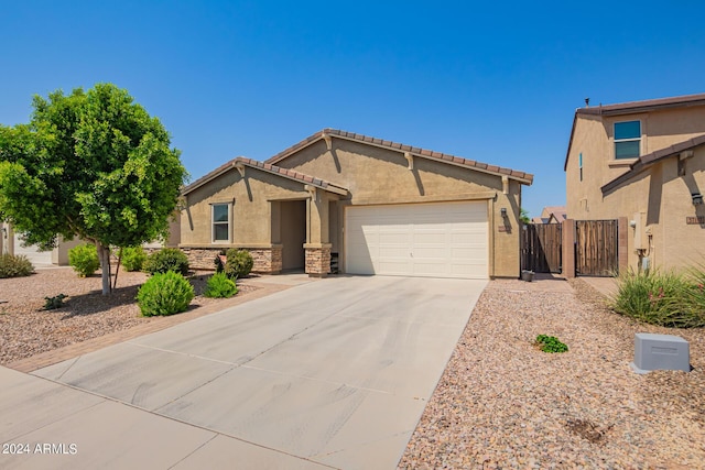 ranch-style home with an attached garage, driveway, stone siding, a gate, and stucco siding