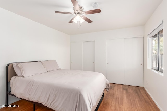 bedroom featuring a ceiling fan, light wood-type flooring, and two closets