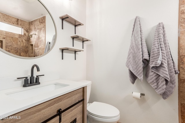 bathroom featuring tiled shower, vanity, and toilet