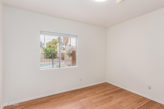 spare room featuring light wood-type flooring and baseboards