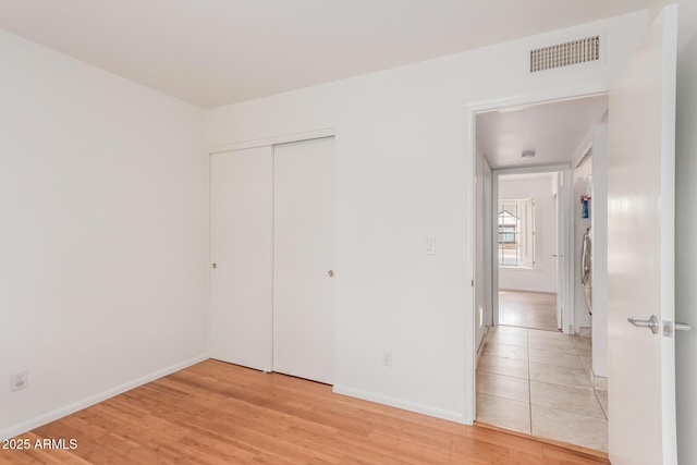 unfurnished bedroom with light wood-type flooring, visible vents, and baseboards