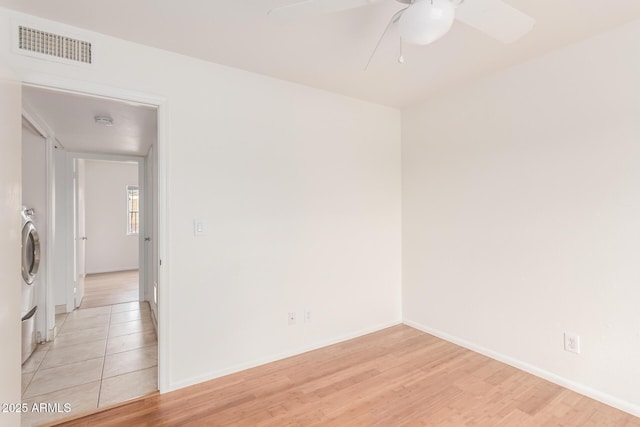 unfurnished room with visible vents, baseboards, a ceiling fan, light wood-type flooring, and washer / clothes dryer