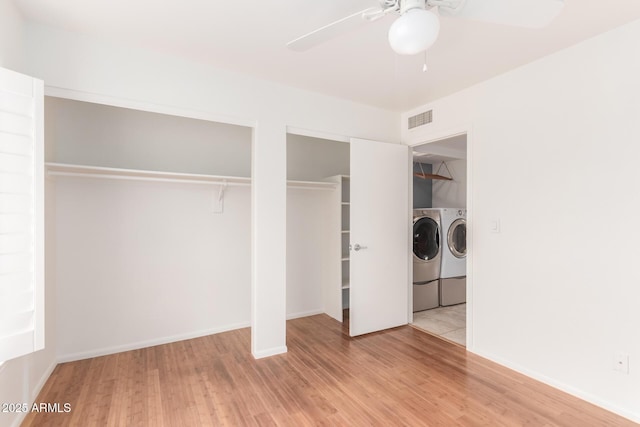 clothes washing area featuring laundry area, visible vents, ceiling fan, wood finished floors, and separate washer and dryer