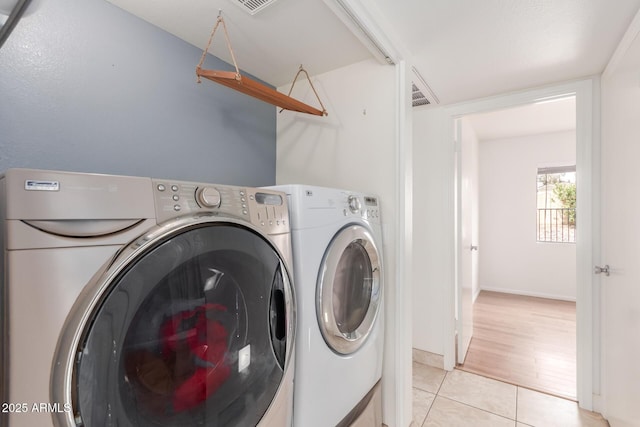 laundry room featuring light tile patterned floors, baseboards, visible vents, and washer and dryer