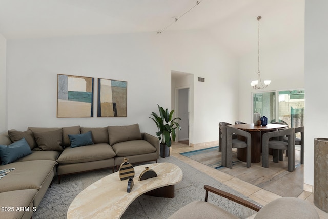 living area with high vaulted ceiling, track lighting, visible vents, and a notable chandelier