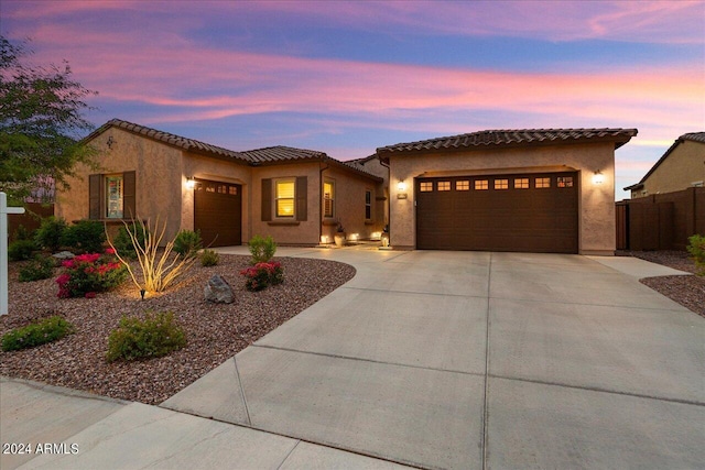 mediterranean / spanish home with driveway, an attached garage, a tiled roof, and stucco siding