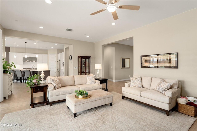 living room with light hardwood / wood-style floors, sink, and ceiling fan