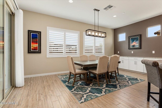 dining space with light hardwood / wood-style flooring and a notable chandelier