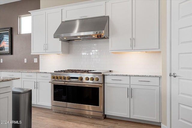 kitchen with range hood, light hardwood / wood-style floors, stainless steel range, and white cabinets