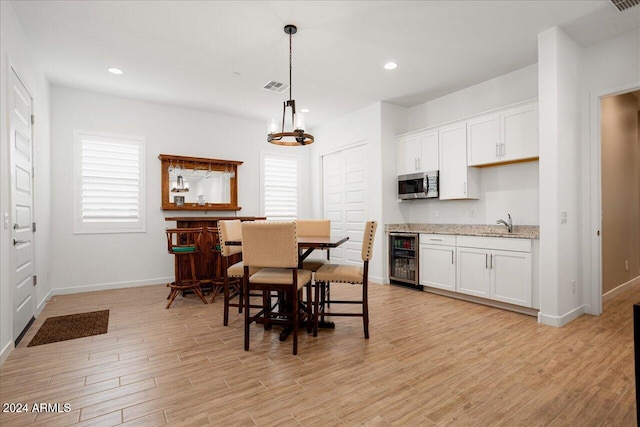 dining space featuring light hardwood / wood-style flooring, wine cooler, and sink