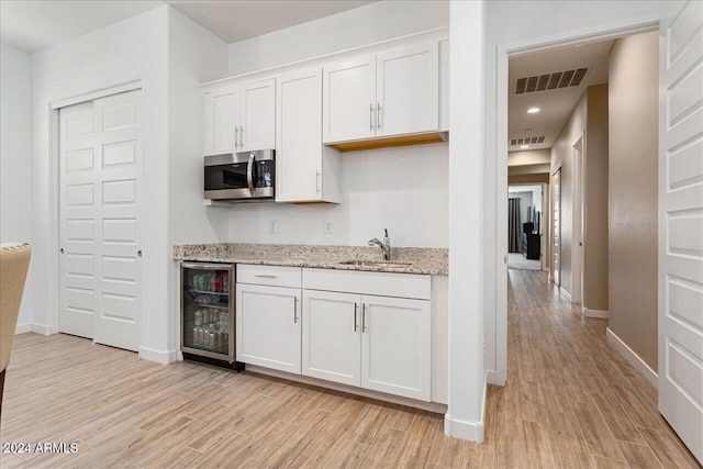 kitchen featuring white cabinetry, light hardwood / wood-style flooring, sink, and beverage cooler