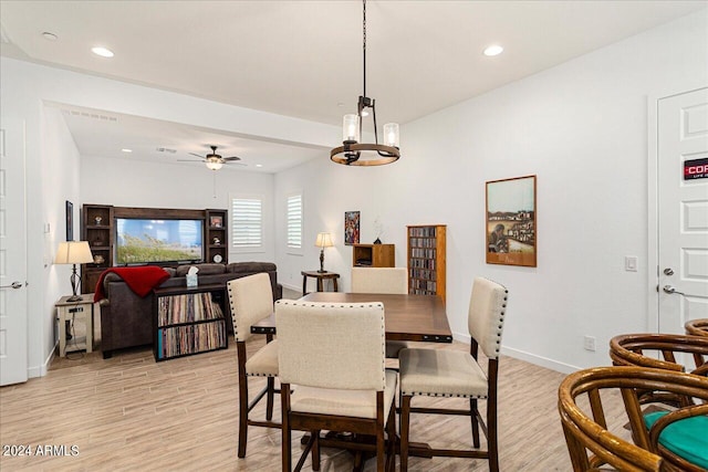 dining room with light hardwood / wood-style flooring and ceiling fan with notable chandelier