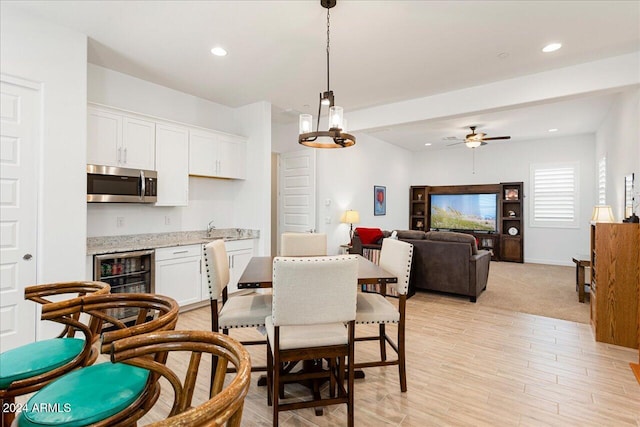 dining area featuring wine cooler, sink, light hardwood / wood-style floors, and ceiling fan