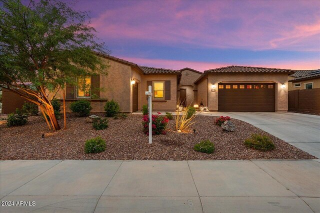 mediterranean / spanish-style house with a tile roof, driveway, an attached garage, and stucco siding