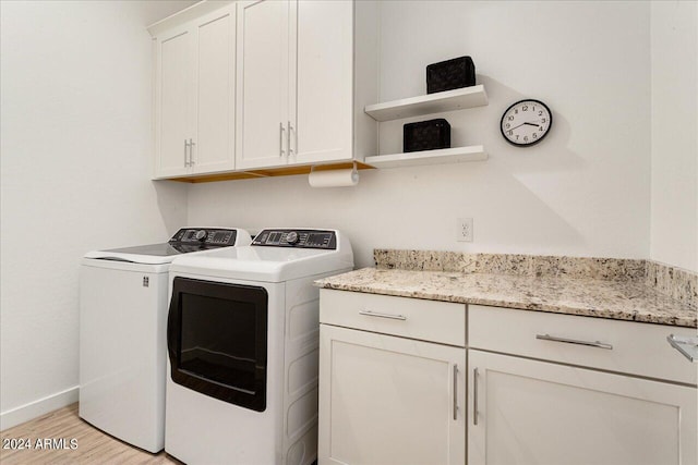 laundry room with washer and dryer, light hardwood / wood-style floors, and cabinets