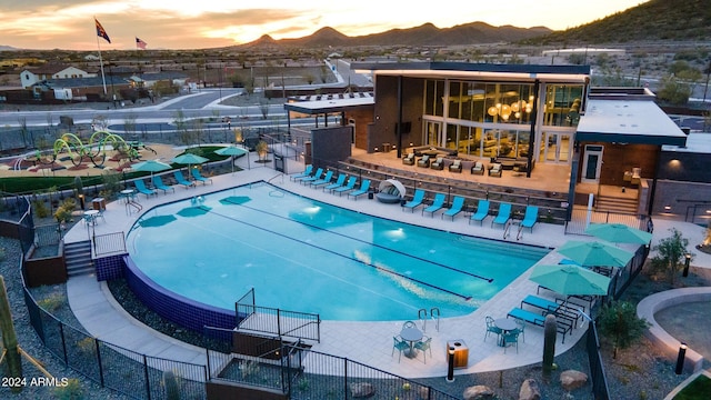 pool at dusk featuring a patio area and a mountain view