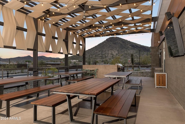 patio terrace at dusk featuring a pergola and a mountain view