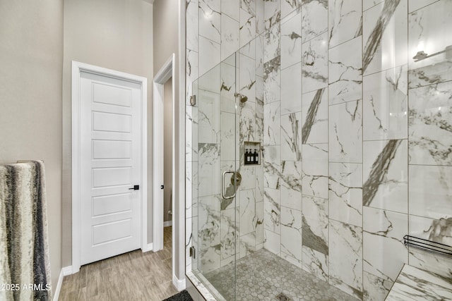 bathroom with wood finished floors, a marble finish shower, and baseboards