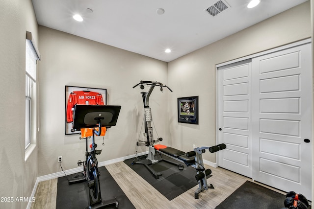 workout room featuring baseboards, visible vents, and wood finished floors