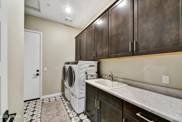 washroom featuring cabinet space, visible vents, baseboards, separate washer and dryer, and a sink