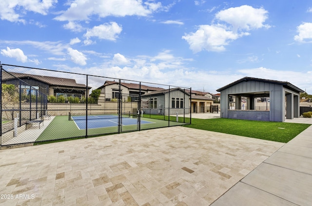 view of basketball court featuring a tennis court, a residential view, a yard, and fence