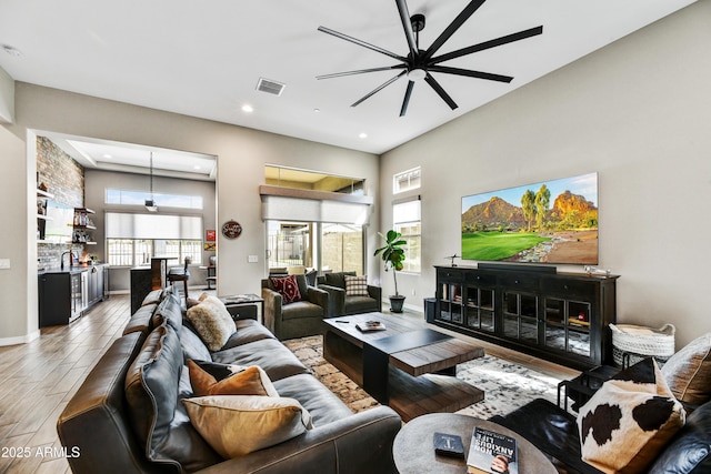 living room featuring recessed lighting, wood finished floors, a towering ceiling, visible vents, and baseboards