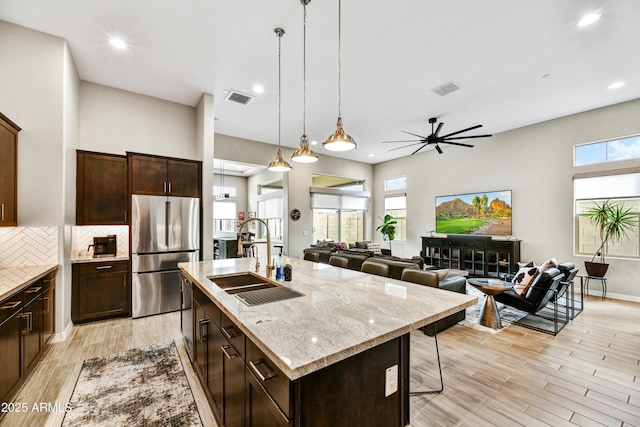 kitchen with light wood-style floors, visible vents, a sink, and freestanding refrigerator