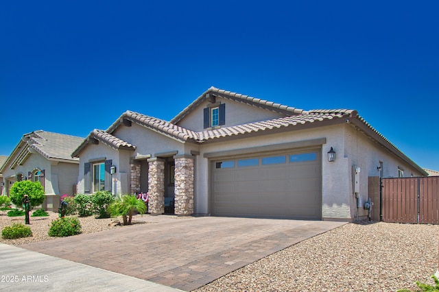 view of front of house featuring decorative driveway, a tile roof, stucco siding, a garage, and stone siding