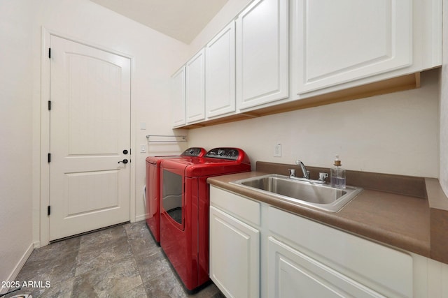 laundry room with a sink, baseboards, cabinet space, stone finish flooring, and washing machine and clothes dryer