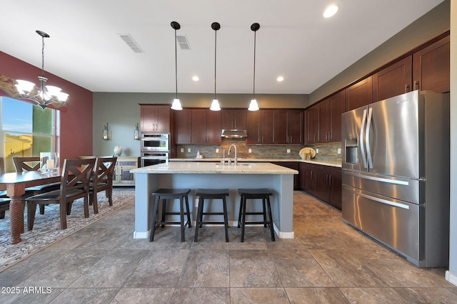 kitchen with tasteful backsplash, visible vents, appliances with stainless steel finishes, under cabinet range hood, and a sink